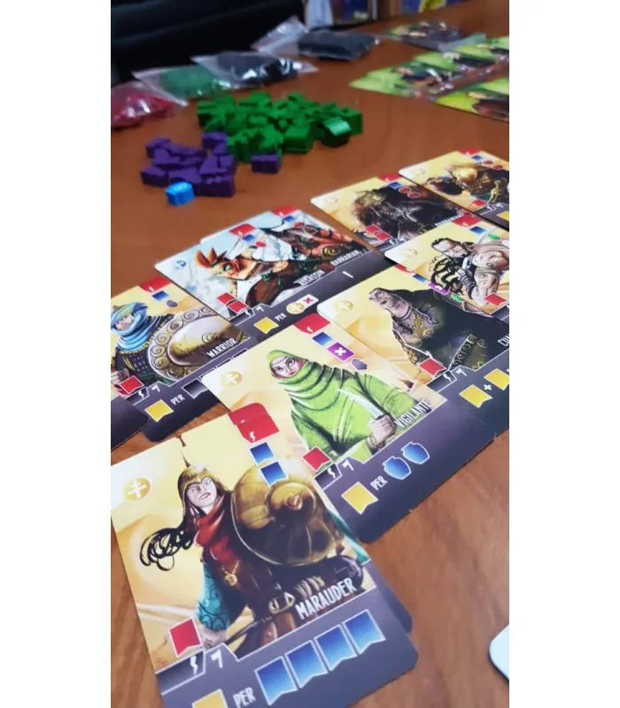 کارت‌های پالادین بازی Paladins of the West Kingdom روی میز چوبی، در کنار مهره‌های سبز و بنفش